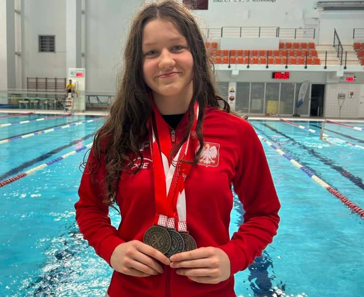 pływaczka z medalami na szyi, w tle kryta pływalnia